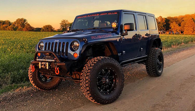 Blue Jeep in corn field at sunset
