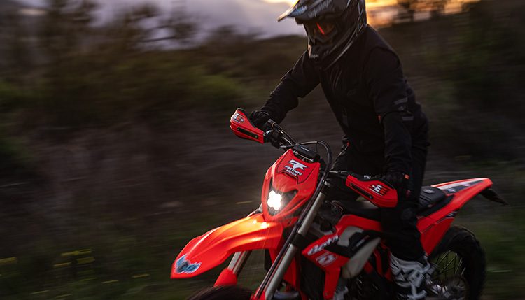 Beta red motorcycle riding at dusk with rider in black.