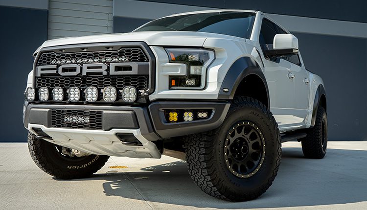 White Ford F-150 Raptor 2017 in front of building with Baja Designs lights