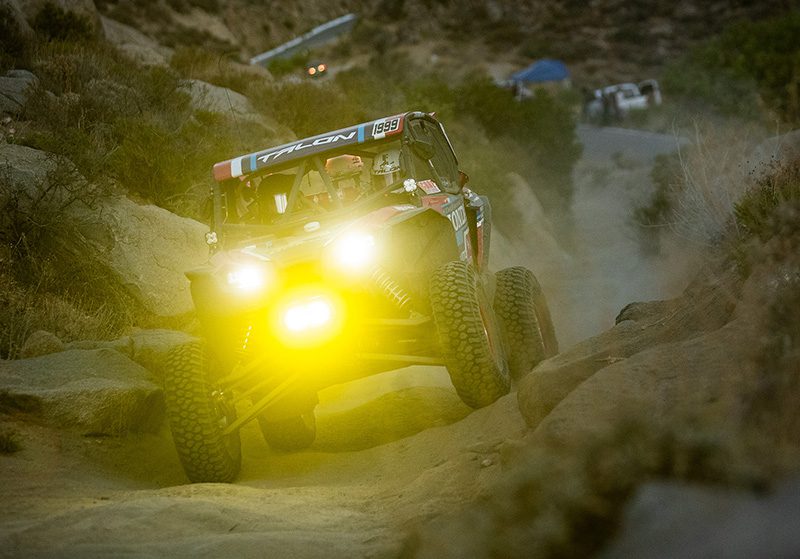 Honda Talon with lights turned on driving on the trail