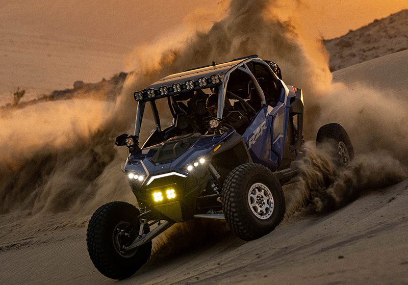 Polaris RZR Pro R in the sandunes at sunset throwing dirt in the air